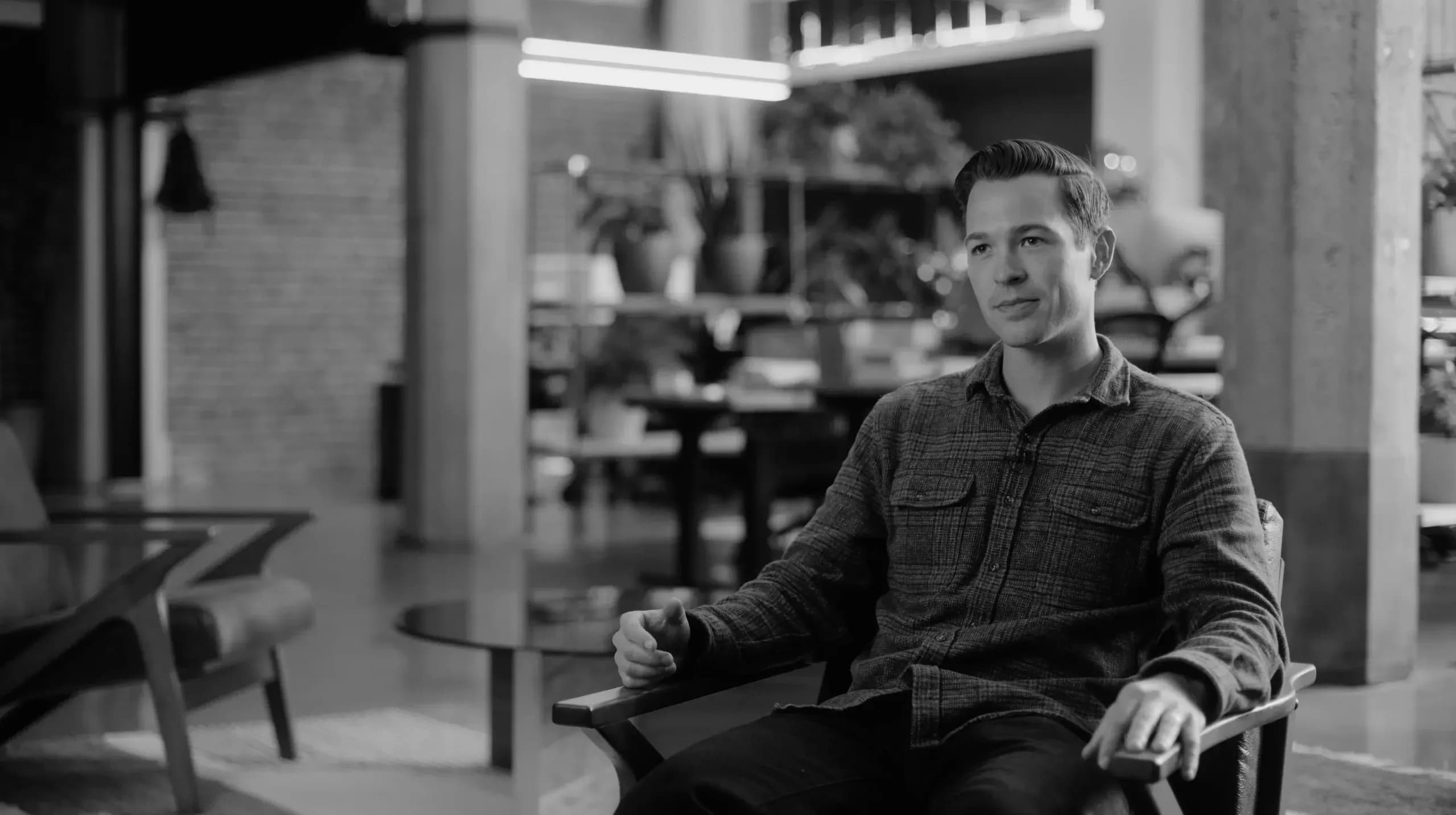 Black-and-white photo of the FTL founder seated in a modern office during an interview.
